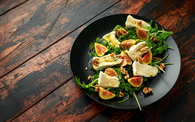 Vegetarian camembert cheese, fig and Arugula, hot rocket salad served on black plate