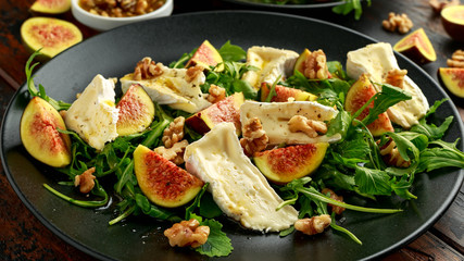 Vegetarian camembert cheese, fig and Arugula, hot rocket salad served on black plate
