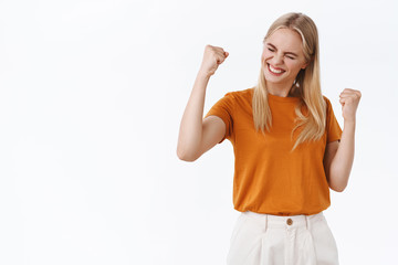 Successful stylish, encouraged blond modern girl with tattoos in orange t-shirt, fist pump and...