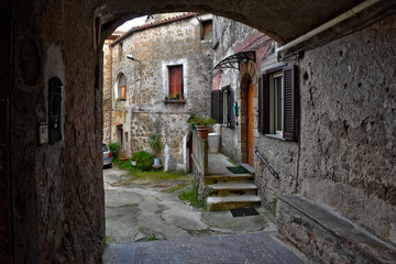 Fototapeta na wymiar A narrow street between the old houses of a mountain village, Italy