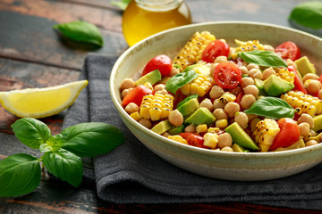 Avocado chickpea salad with grilled sweet corn, tomato and basil. Healthy vegan food