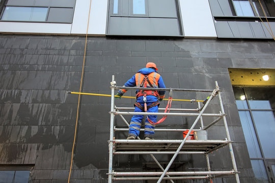 Penthouse Construction. building under restoration. scaffoling on building facade. residential building. High-rise modern apartment construction with flat roof. Workers in a cradle. 