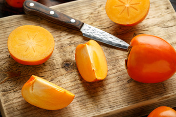 Raw ripe persimmons fruits slices on wooden board