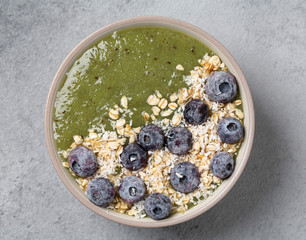 Detox Green Smoothie with Banana, blueberries, kiwi, spinach and granola in a Bowl. Healthy Breakfast. Vegan food, top view