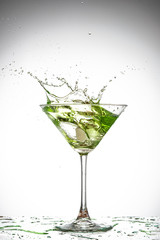 martini glass and splash from falling ice on a white background