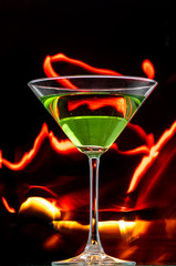 martini glass on black background and lines of fire in the dark