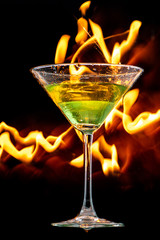 martini glass on black background and lines of fire in the dark