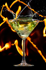 ice falls on a martini glass on a black background and lines of fire in the dark