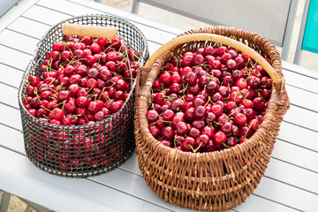 two baskets filled with beautiful red cherries on a garden table