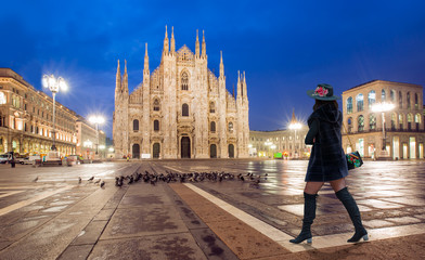 Woman in black clothes with black hat is walking on the street - Duomo di Milano (Milan Cathedral) and Piazza del Duomo in the Morning, Milan, Italy