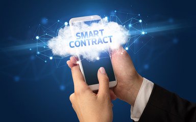 Female hand touching smartphone with SMART CONTRACT inscription, cloud business concept