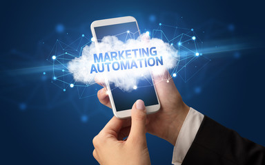 Female hand touching smartphone with MARKETING AUTOMATION inscription, cloud business concept