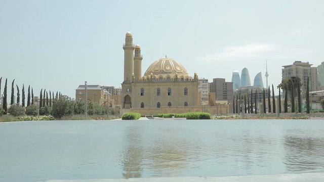 Taza Pir Mosque Baku. View of the mosque through the fountain. Summer sunny day. View of Baku through the natural landscape.