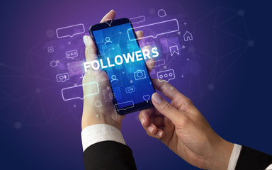Female hand typing on smartphone with FOLLOWERS inscription, social media concept