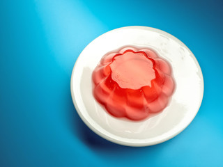 red berry jelly in a white plate on a blue background. the view from the top
