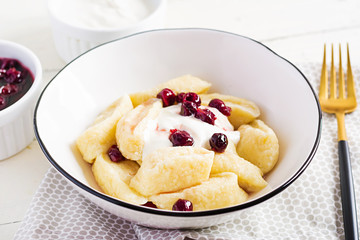 Traditional  ukrainian / russian cottage cheese lazy dumplings served with sour cream and cherry jam on white wooden background.