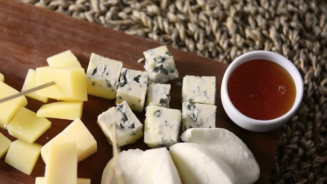 Cheese plate. Wooden Board with several types of cheese and honey. 