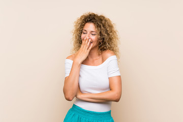Young blonde woman with curly hair over isolated background smiling a lot © luismolinero