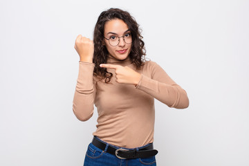 young pretty woman looking impatient and angry, pointing at watch, asking for punctuality, wants to...