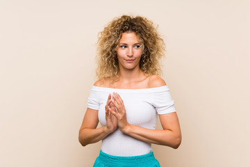 Young blonde woman with curly hair over isolated background scheming something