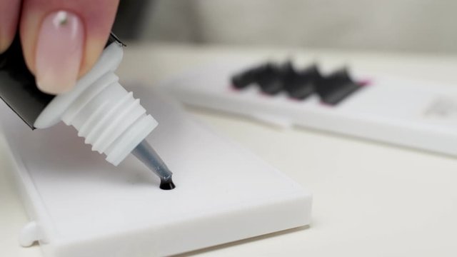 Eyelash Extension Procedure. Close-up of a master at work artificial eyelash extensions material. Hands of the master pouring glue