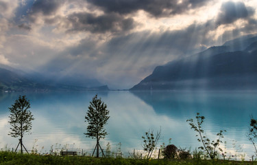 Beautiful blue lake and houses with the brown roofs in Alps in Switzerland are in the sunlight