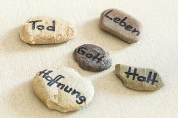 Steine mit Aufschrift liegen im Sand