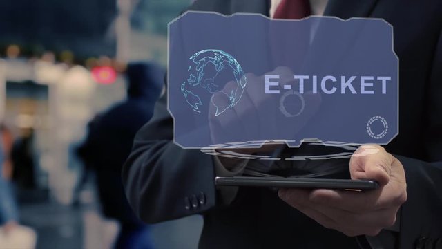 Unrecognizable businessman uses hologram on smartphone with text E-ticket. Man in shirt and jacket with holographic screen on background of entrance to the airport or train station
