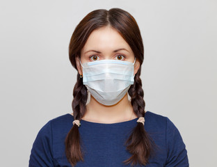 Beautiful young girl with pigtails in a protective medical mask