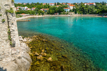 Fototapeta premium Wall of the fortress with amazing beach in Krk town. Krk town is a famous touristic destination on Krk island, Croatia. Space in right side