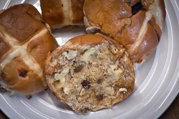Hot cross buttered buns on a plate placed on a wooden table