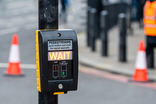 Crosswalk button for pedestrian with light warning on a defocused background , London, UK