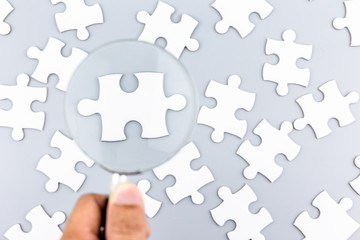 Magnifying glass to find piece of jigsaw puzzle