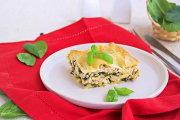Lasagna with salmon and spinach on a clay plate on a light concrete background. Italian food. Pasta Recipes