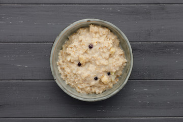 A bowl of nutritious blueberry and apple porridge shot from above on a dark wooden background