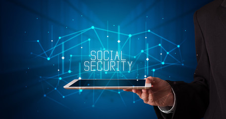Young business person working on tablet and shows the digital sign: SOCIAL SECURITY