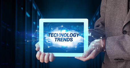 Young business person working on tablet and shows the inscription: TECHNOLOGY TRENDS