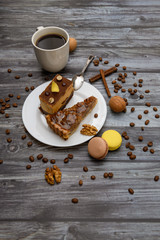 Cup of coffee and two slices of cake and macaroons on the plate on wooden table