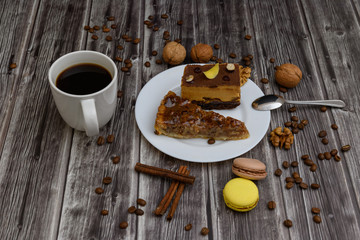 Cup of coffee and two slices of cake and macaroons on the plate on wooden table