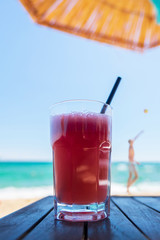 Cocktail on the beach. Fresh juice of watermelon in the background of the sea and a volleyball player