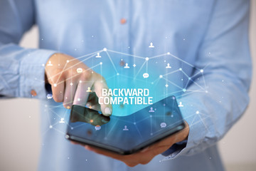 Businessman holding a foldable smartphone with BACKWARD COMPATIBLE inscription, new technology concept