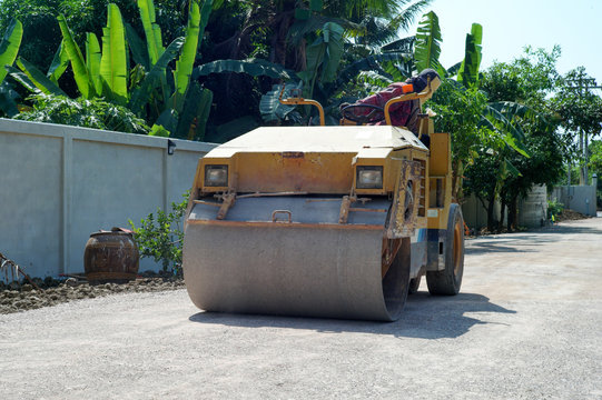 Worker drives the road roller on the crash stone road for preparaing the surface