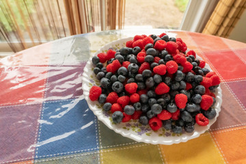 plate on the table with fresh raspberries and blueberries