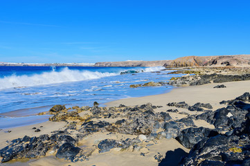 View of beautiful Playa de la Cera beach, blue sea, yellow sand, cliffs. Papagayo, Playa Blanca, Lanzarote, Canary Islands, selective focus