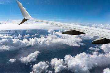 Fototapeta premium White clouds sail under the wing of an airplane