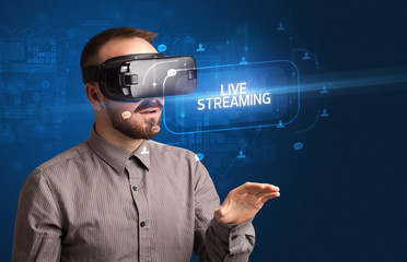 Businessman looking through Virtual Reality glasses with LIVE STREAMING inscription, social networking concept