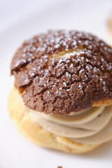 choux cream or cream puff or French profiteroles with fresh cream set on cafe table.