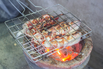 The Grilled squid,Three Grilled squid on gridiron,Delicious bar b Que sea food.