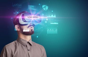 Businessman looking through Virtual Reality glasses with NOW HIRING inscription, new business concept