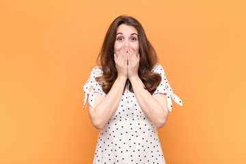 young pretty woman happy and excited, surprised and amazed covering mouth with hands, giggling with...